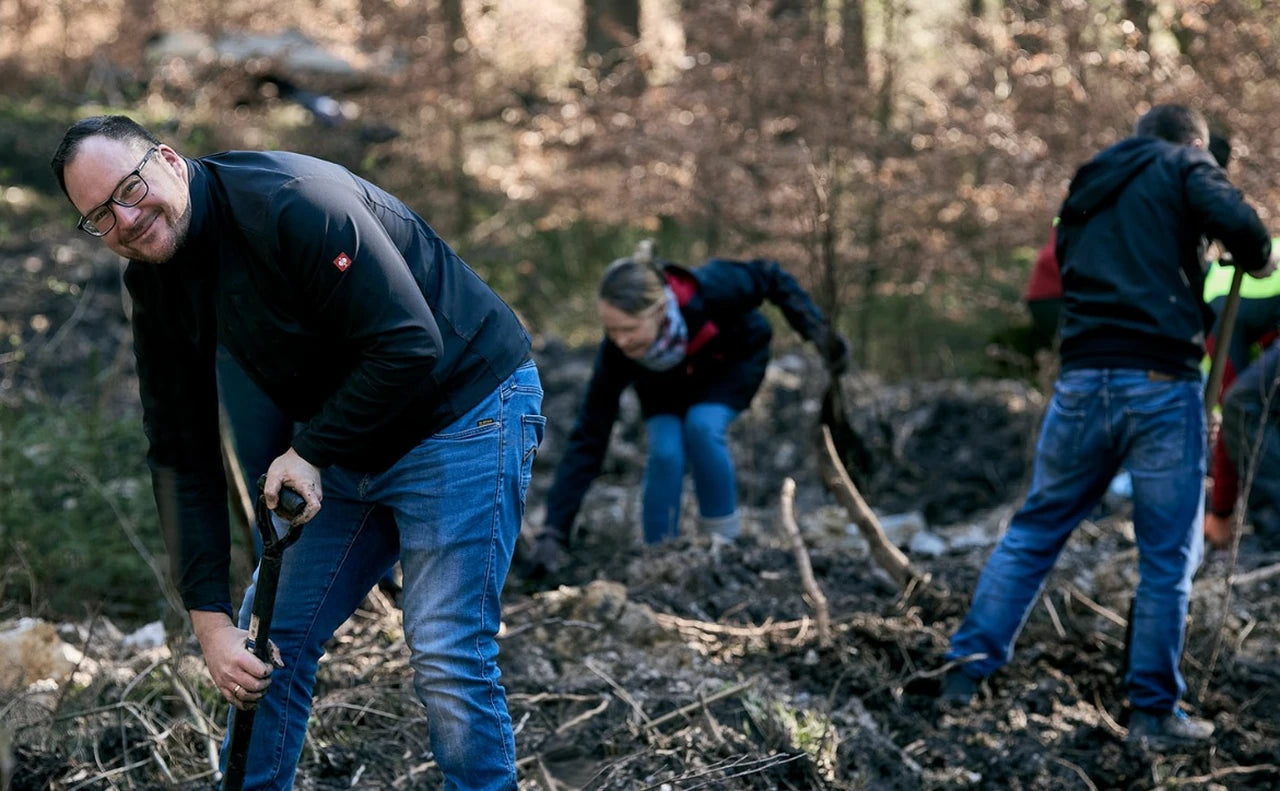 Menschen mit Spaten bei einer gemeinsamen Pflanzaktion im Wald