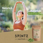 Eine junge Frau in Sportkleidung mit erhobenen Armen, im Hintergrund blauer Himmel. Text: Natürlich fit/Natürlich wohlfühlen SPINTZ Bio Chlorella Presslinge im plastikfreien Doypack – 100 % naturbelassen und aus kontrolliert biologischem Anbau