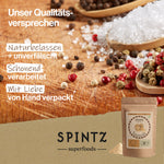 SPINTZ Superfoods Qualitätsversprechen mit naturbelassenen, unverfälschten Zutaten, schonend verarbeitet und mit Liebe von Hand verpackt, dargestellt mit verschiedenen Gewürzen und Beeren in Holzlöffeln